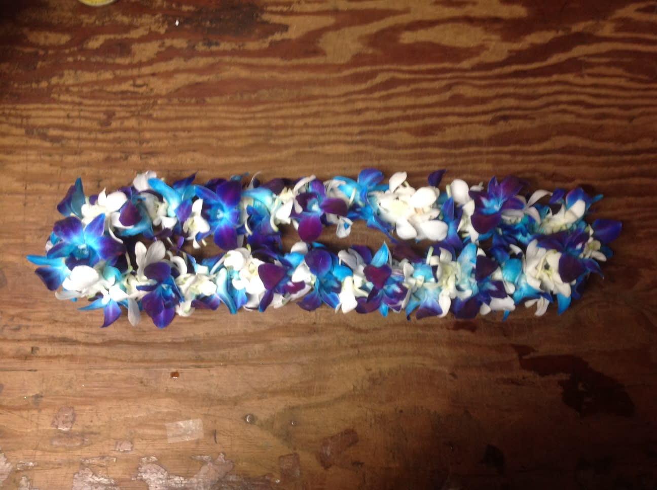 Blue, purple, and white flower lei on a wooden surface