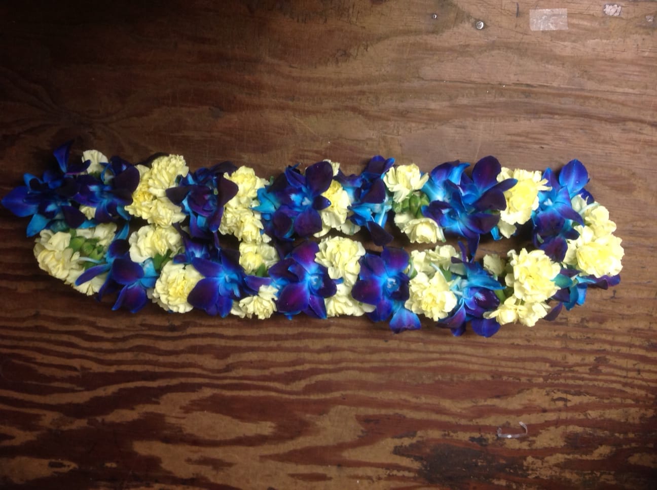 Blue orchids and pale yellow carnations arranged in a long garland