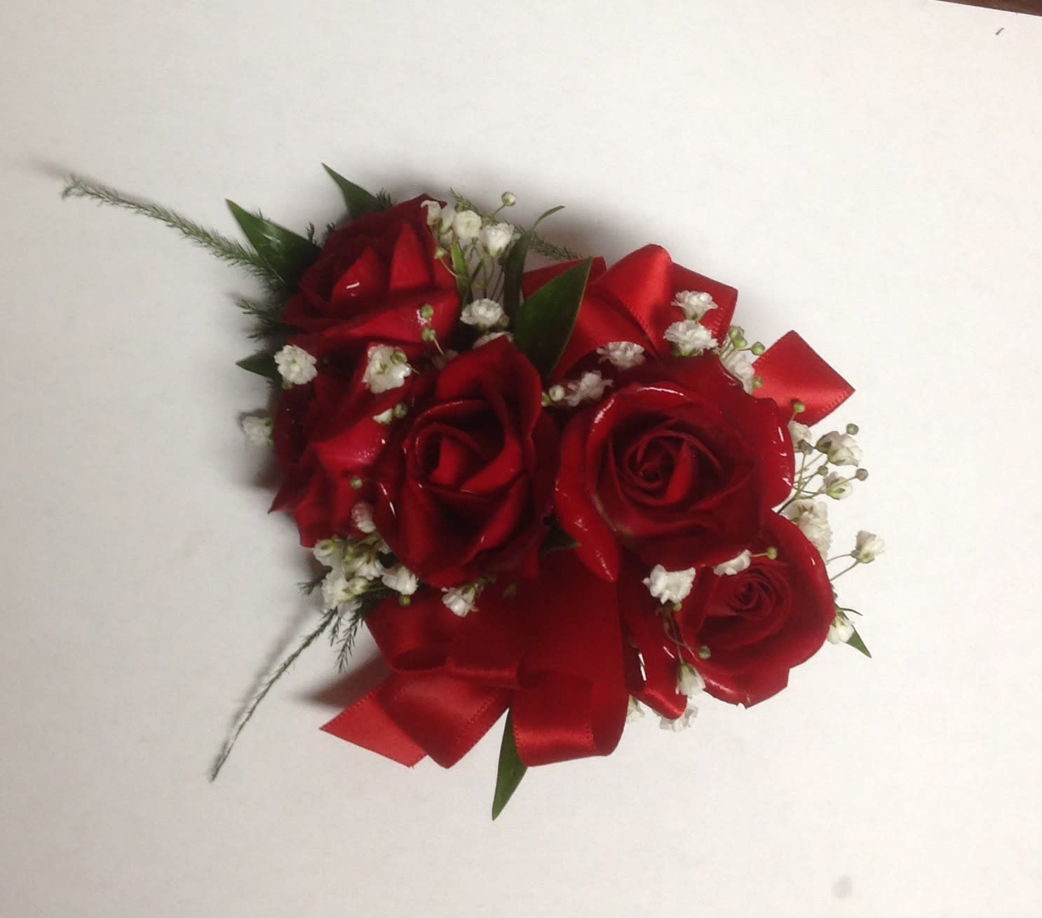 Red rose corsage with white baby's breath and ribbon