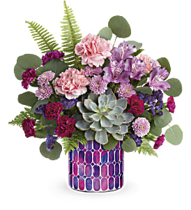Mixed pink and purple flowers in a patterned vase with a succulent centerpiece