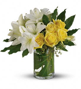 White lilies and yellow roses in a clear glass vase