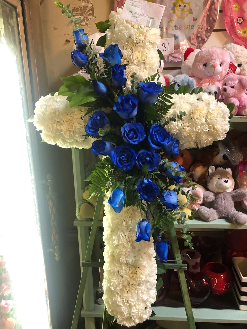 Cross-shaped floral arrangement with blue roses and white carnations