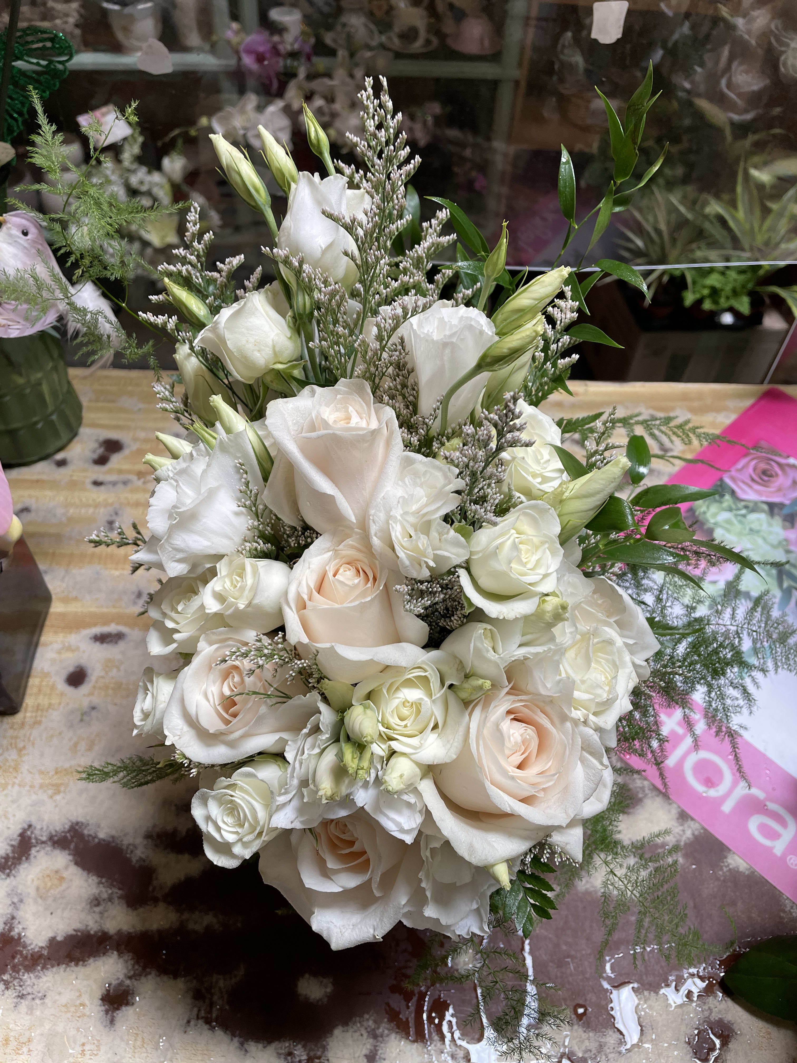 Bouquet of white and blush roses with white lisianthus and greenery