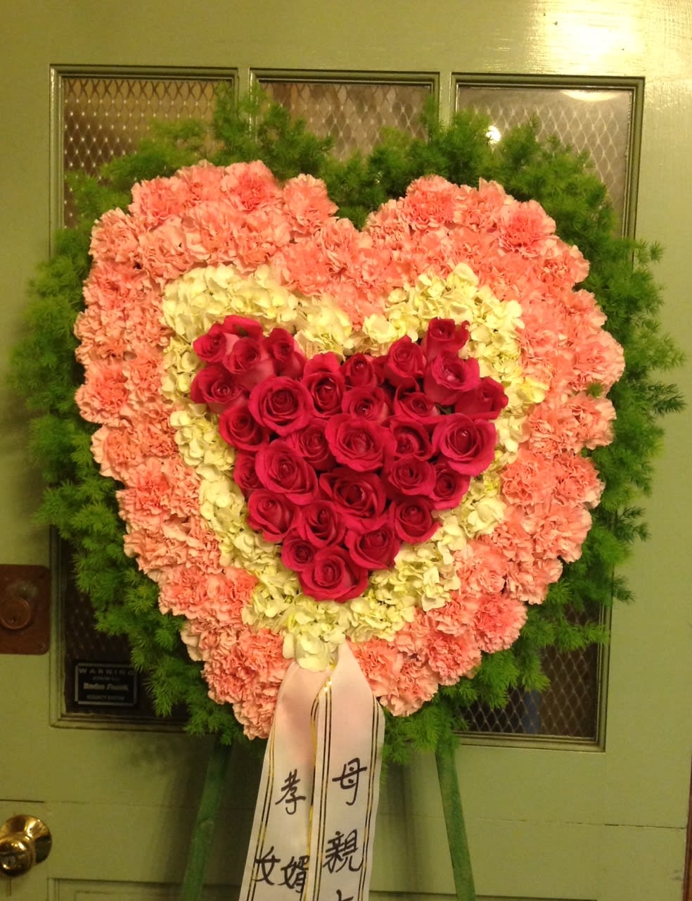 Heart-shaped standing floral spray with red roses and pink carnations