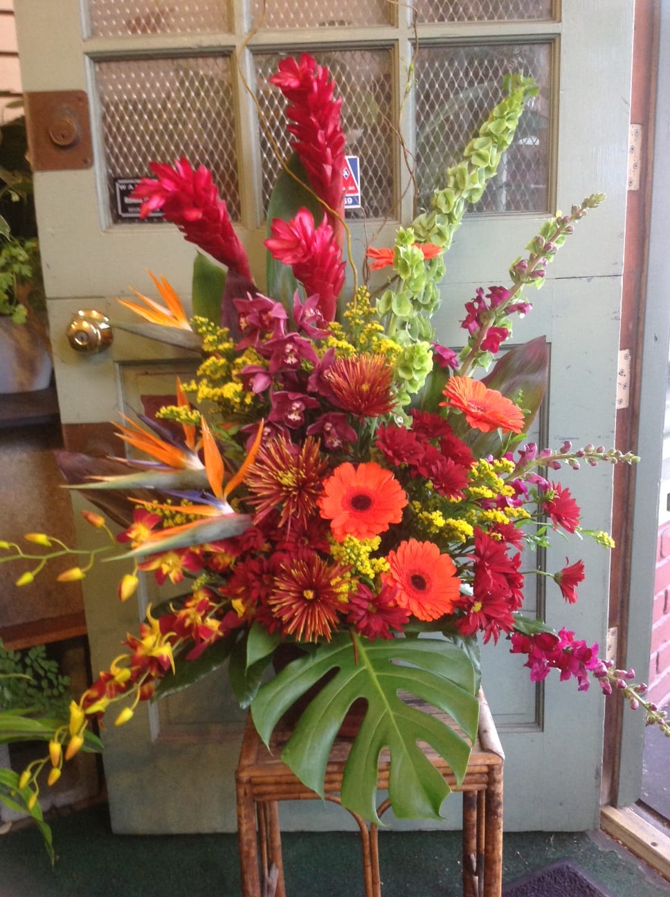 Tropical flower arrangement with orange gerberas and red blooms in a vase