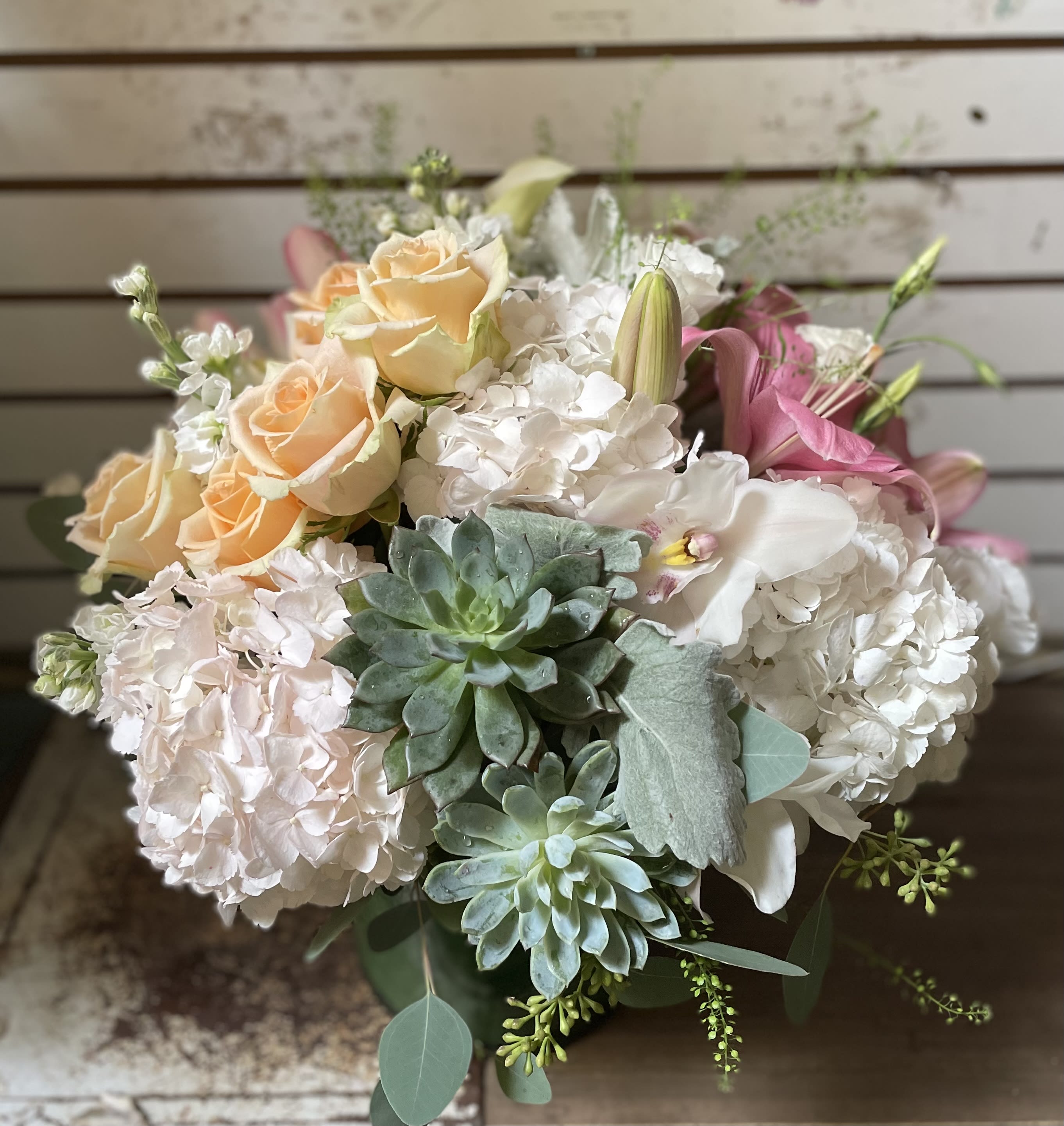 Bouquet of peach roses, white hydrangeas, pink lilies, and succulents