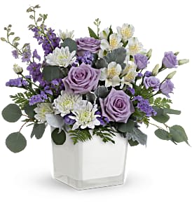 Lavender roses and white flowers in a white square vase