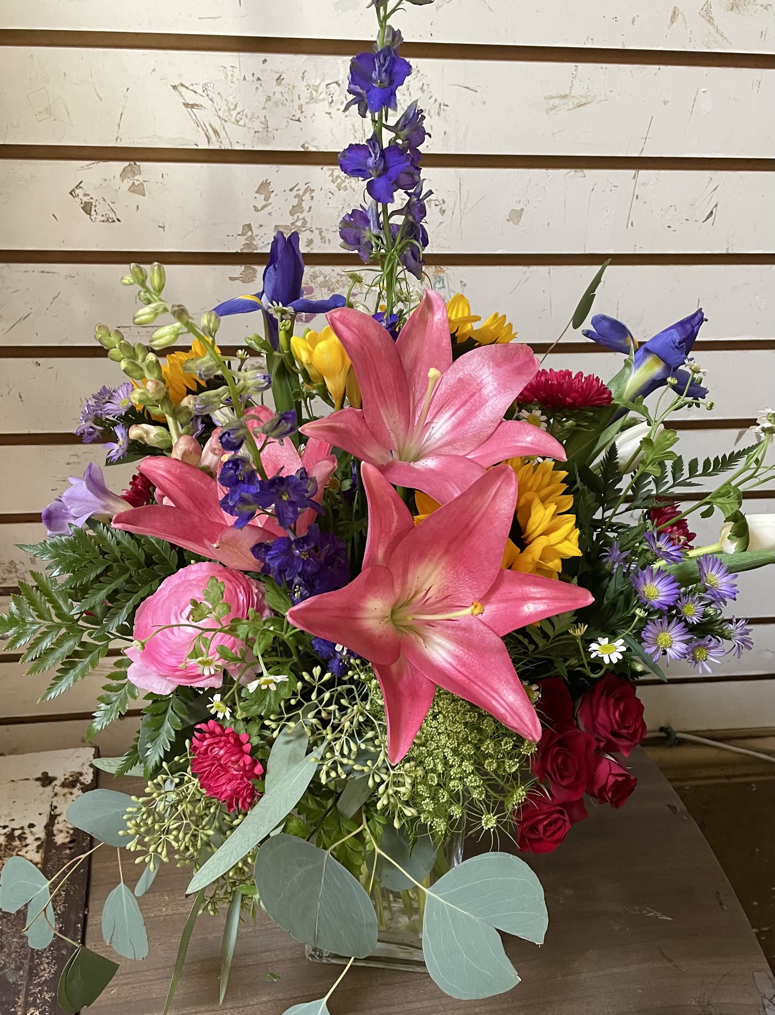 Mixed bouquet with pink lilies, roses, and purple flowers in a glass vase