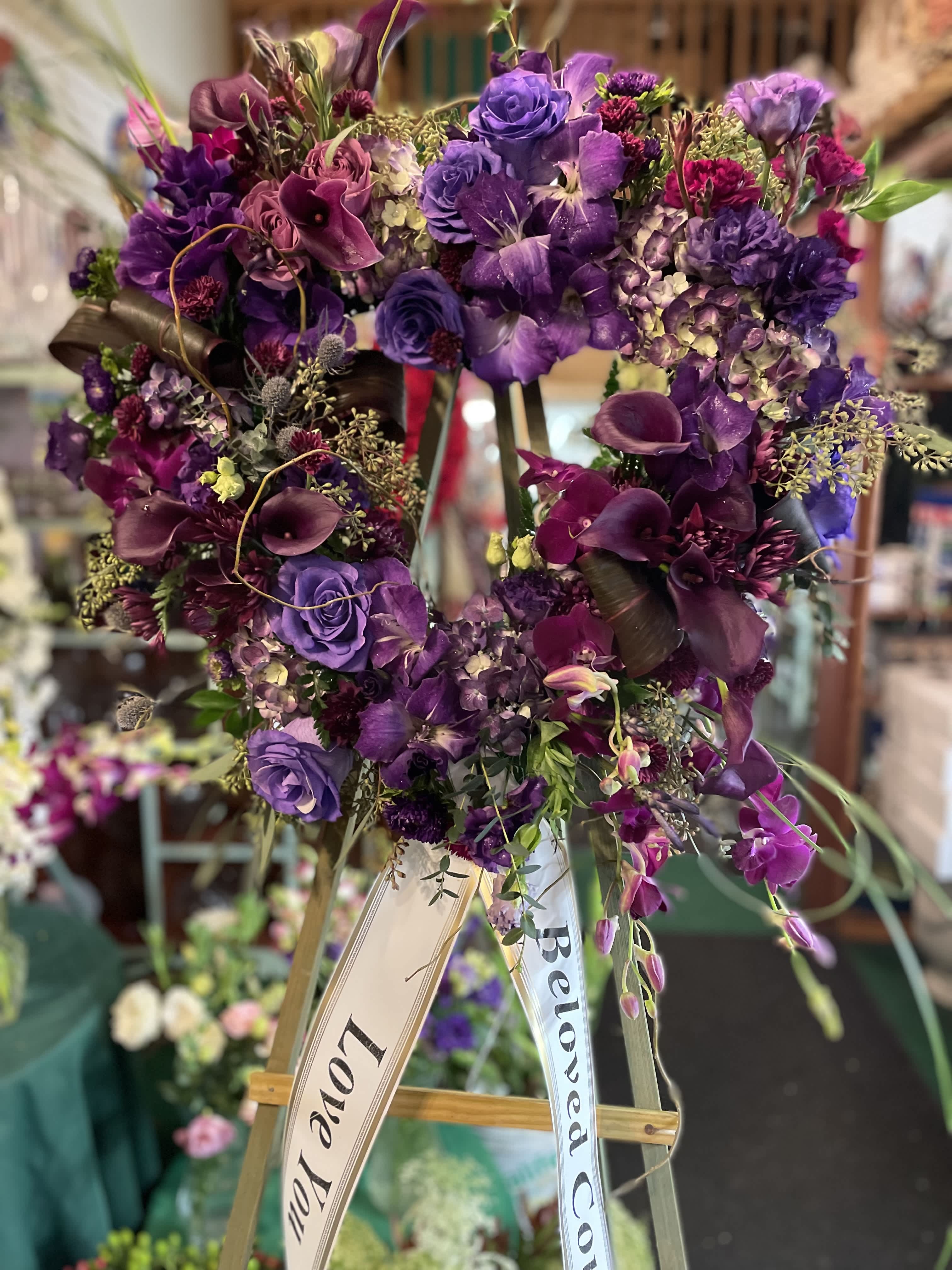 Purple floral heart wreath on an easel with ribbon banners
