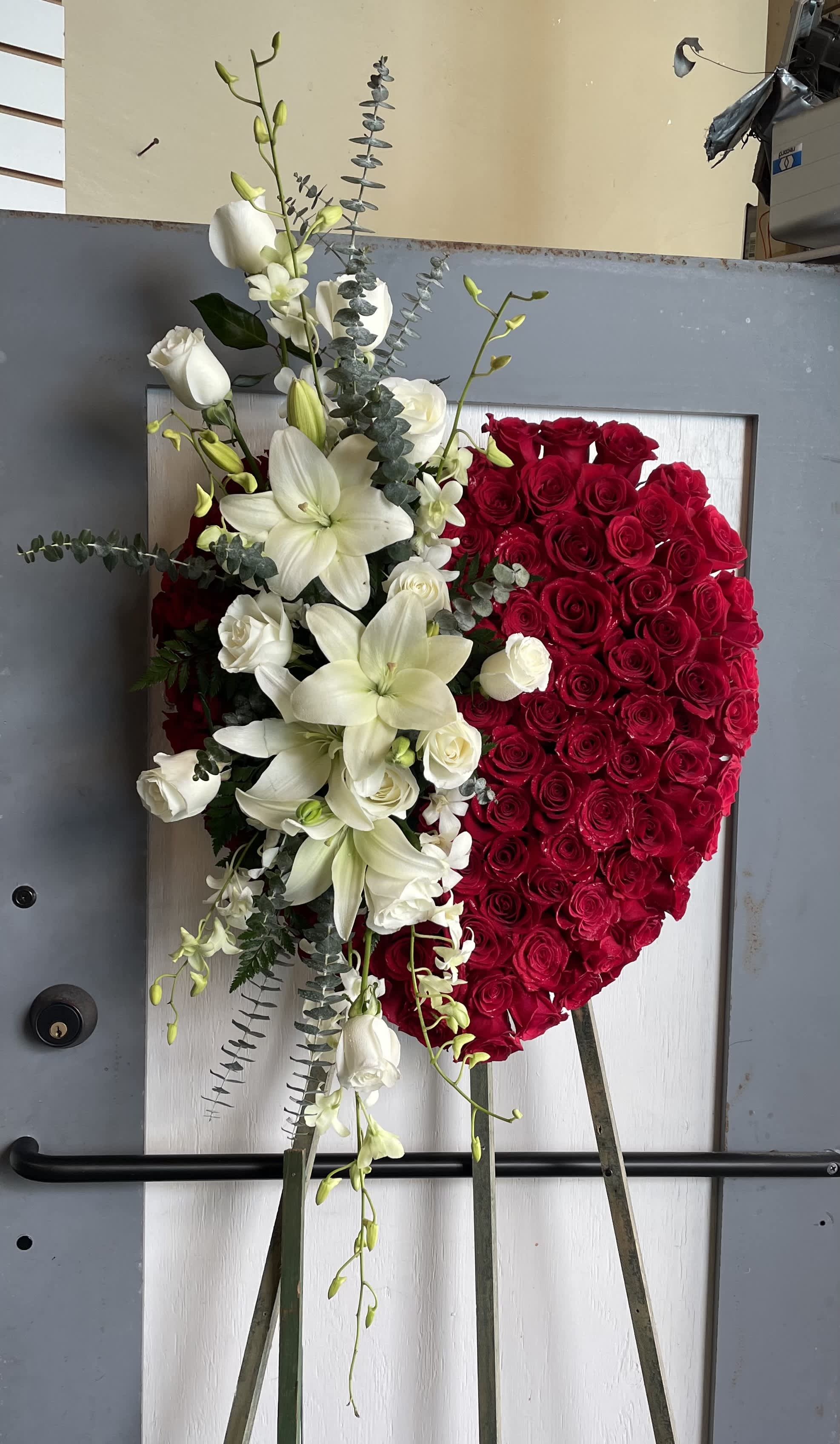 Heart-shaped red rose arrangement with white lilies and roses on an easel