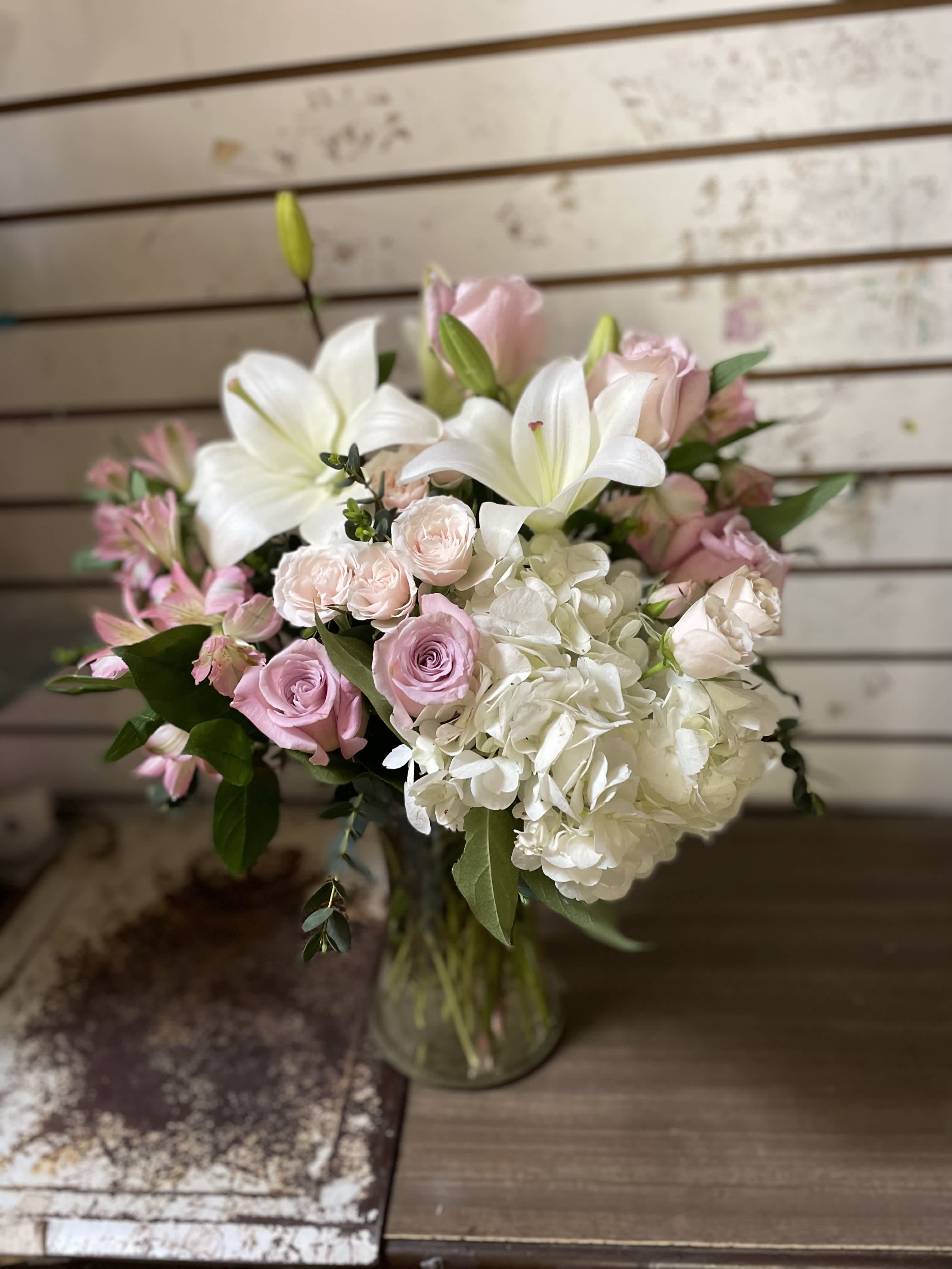 Pink and white bouquet with lilies, roses, and hydrangea in a glass vase