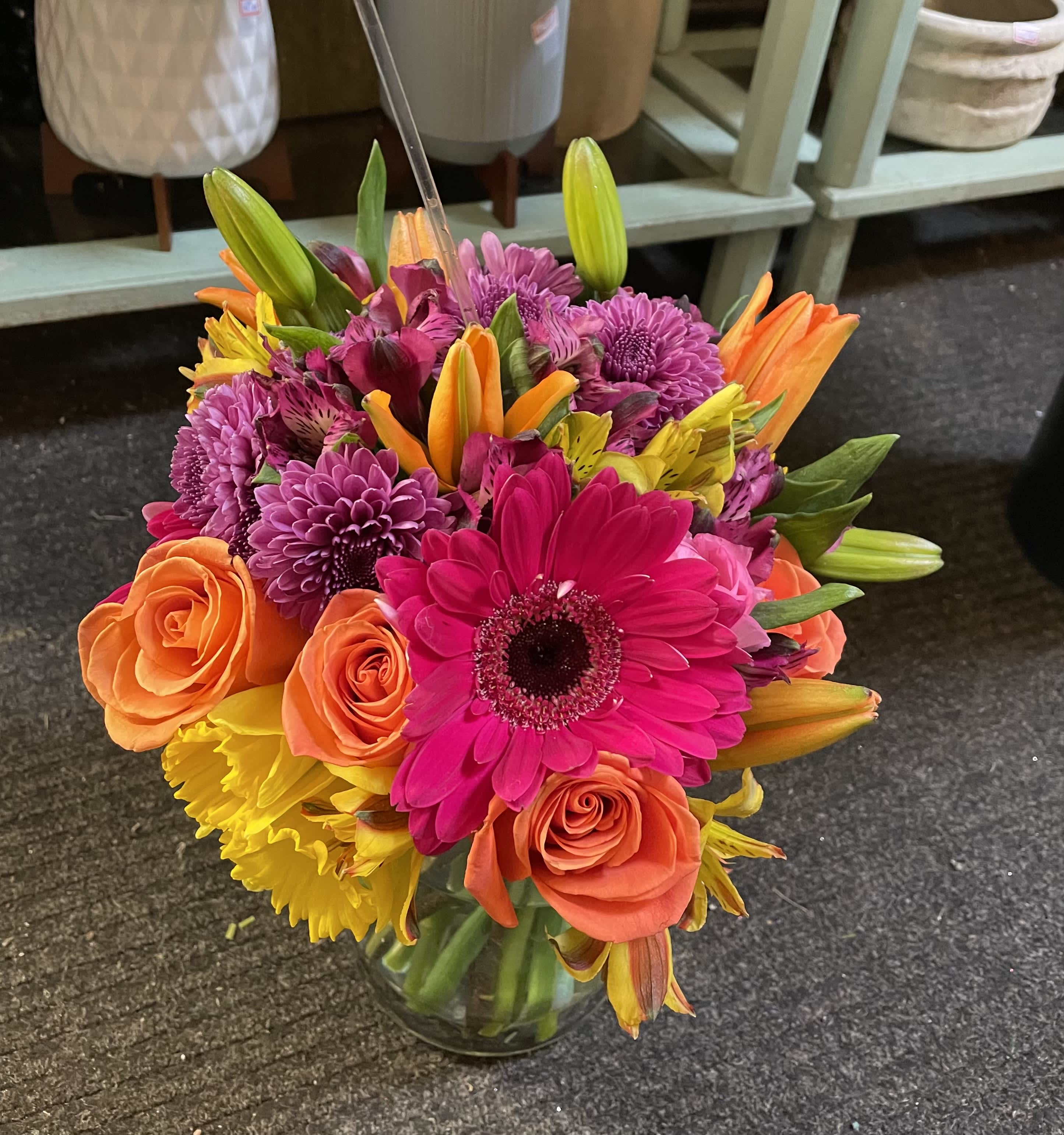 Bright mixed bouquet of pink, orange, and yellow flowers in a glass vase