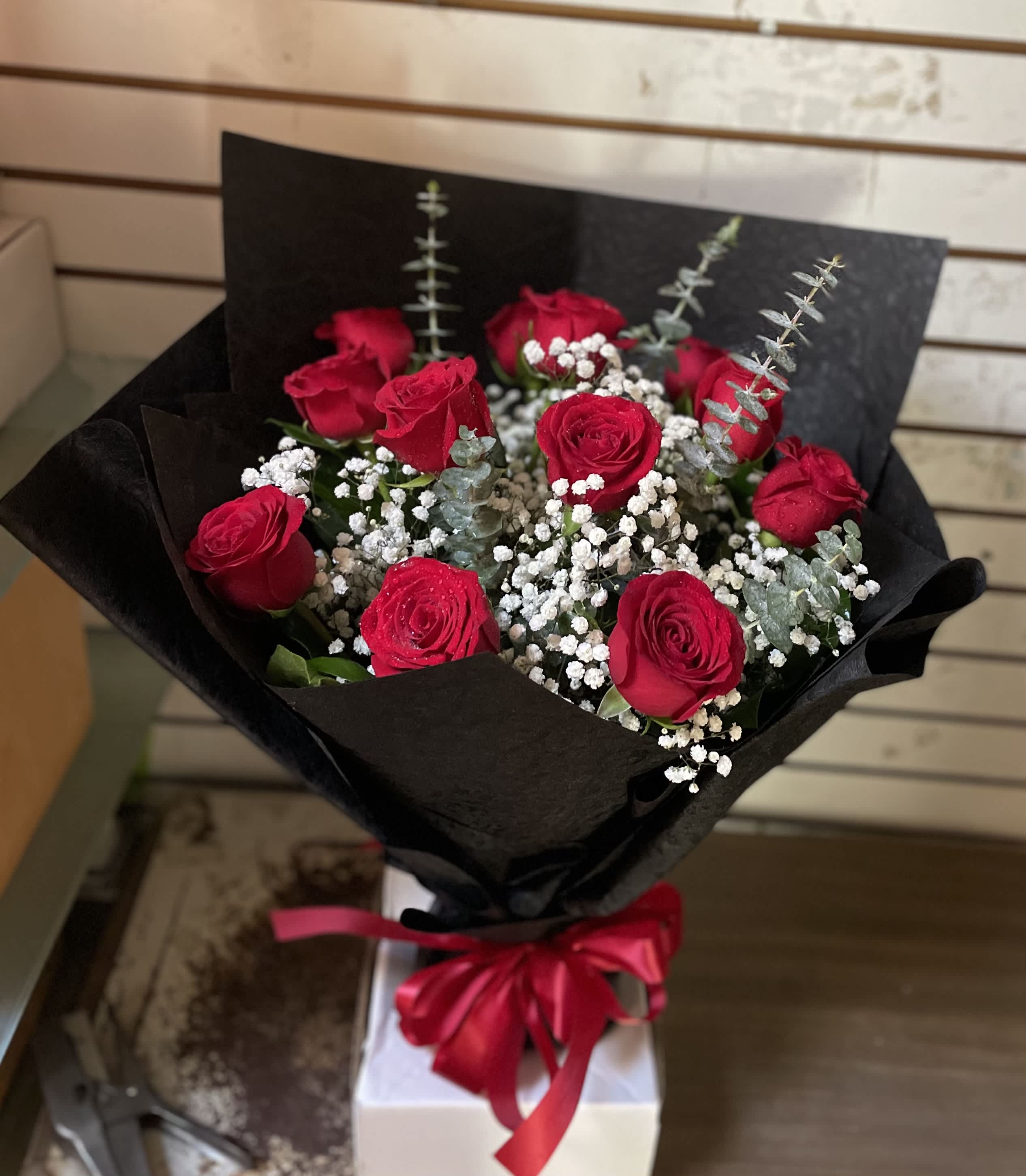 Bouquet of red roses with baby's breath in black wrap and a red ribbon