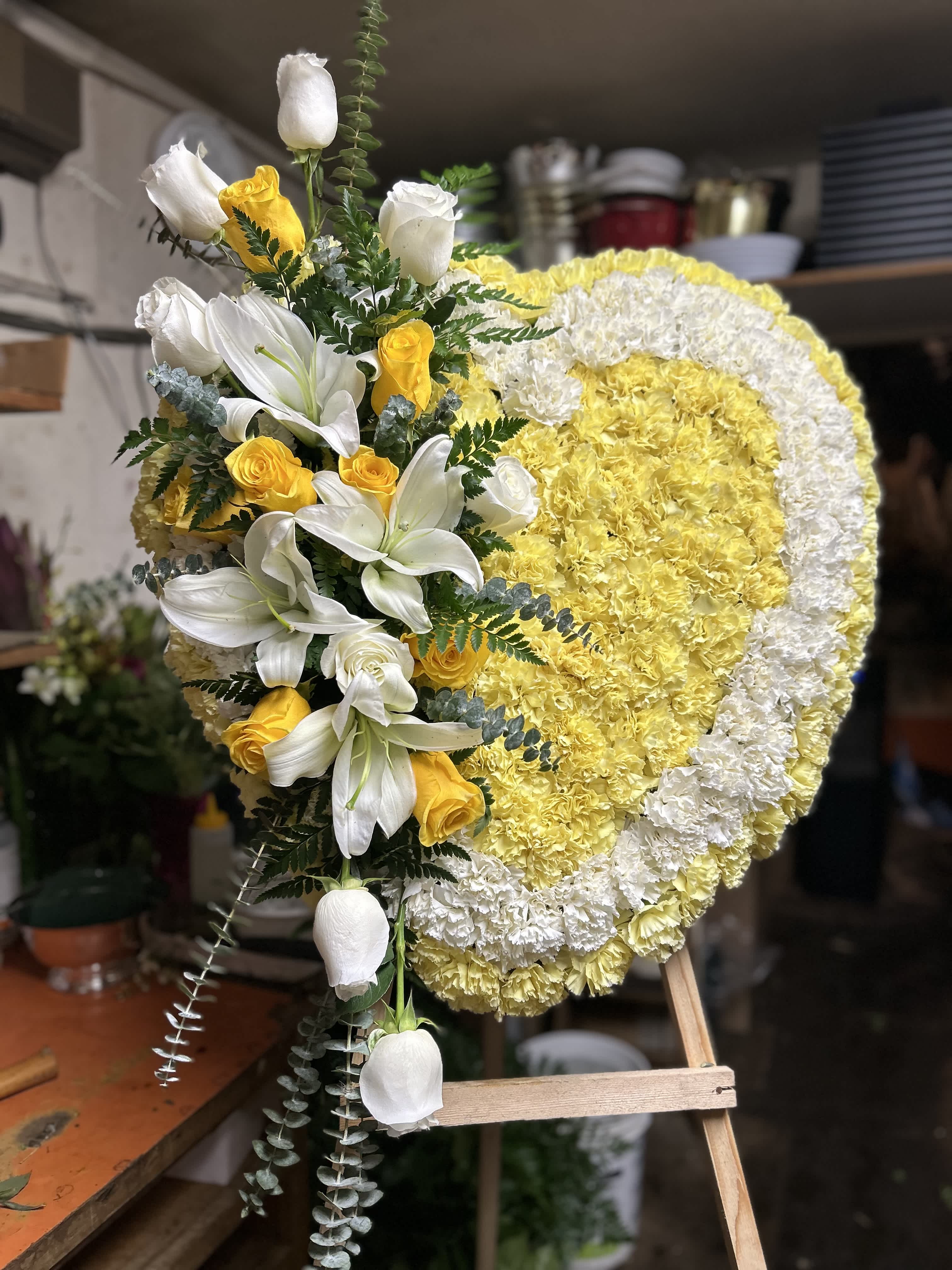 Heart-shaped floral wreath with white lilies and yellow roses