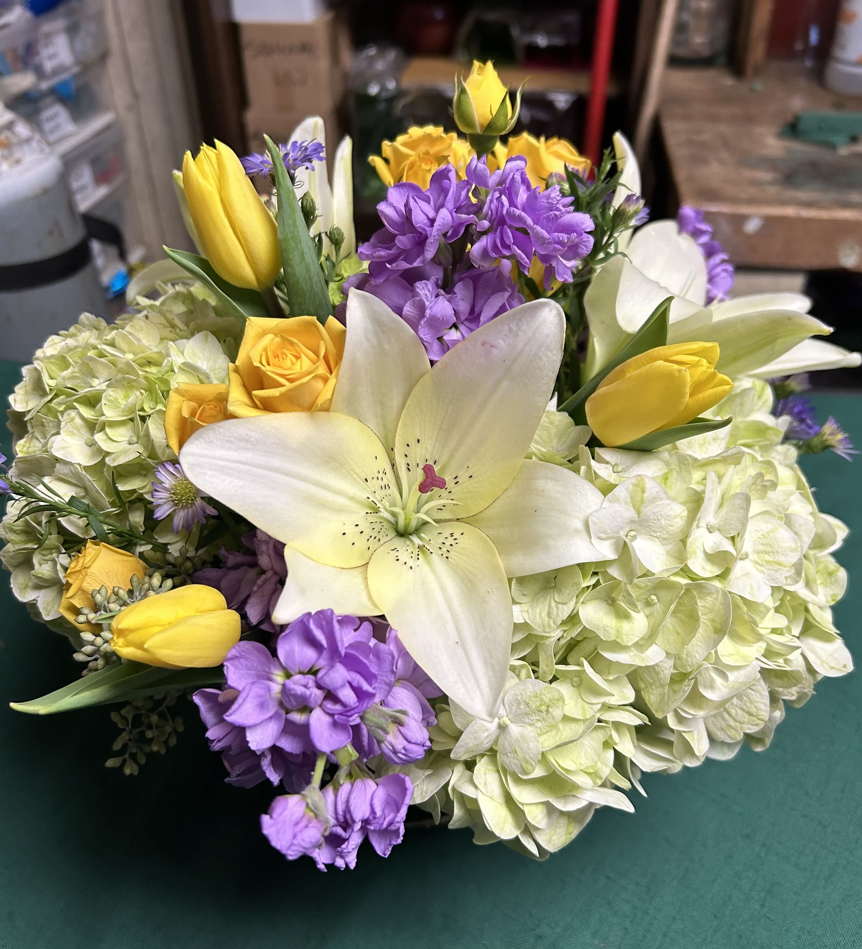 Bouquet of white lilies, yellow tulips, purple flowers, and pale hydrangeas