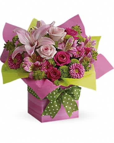 Bright pink and green mixed flower arrangement in a pink gift box with a green polka-dot bow