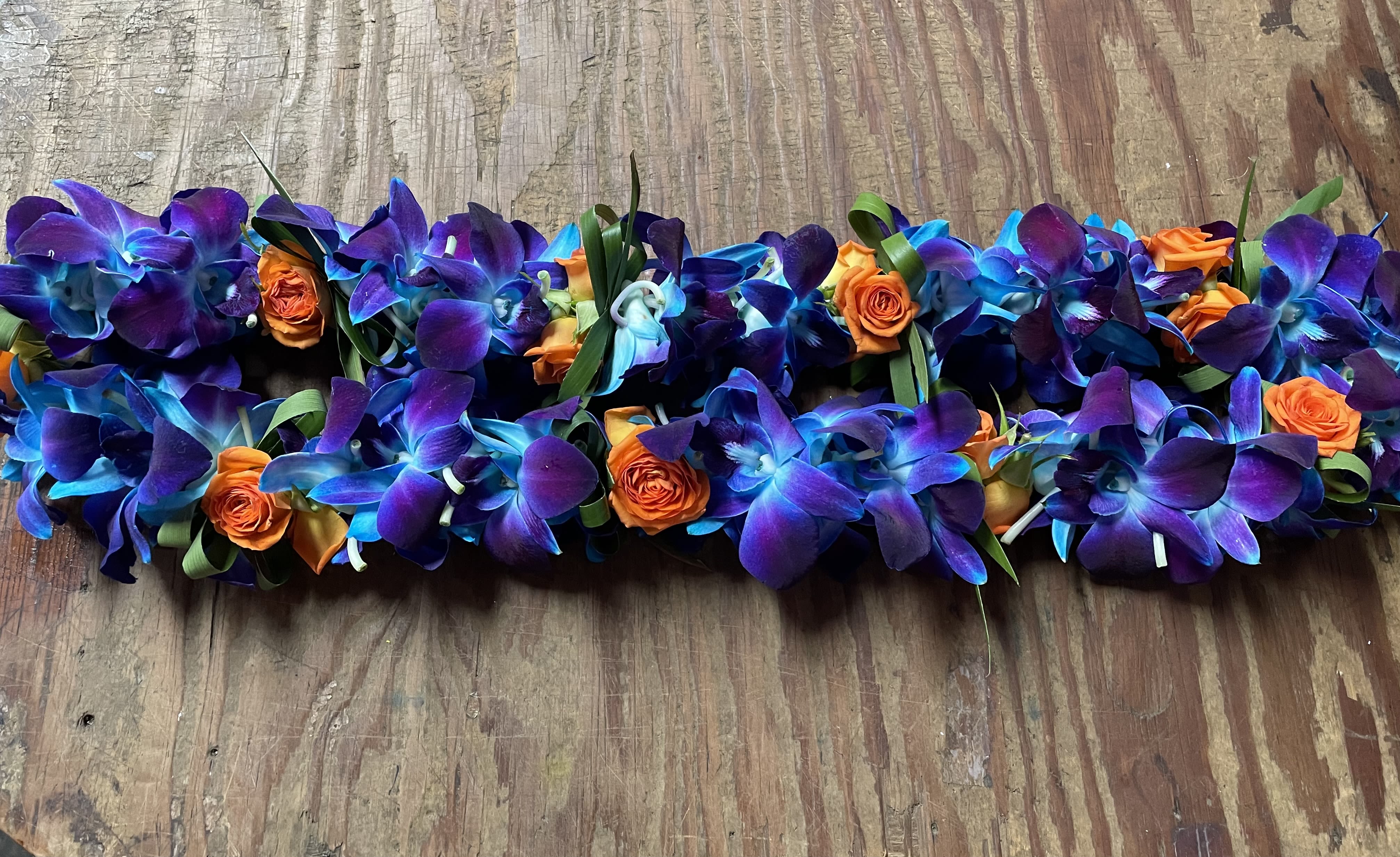 Purple and blue orchid garland with small orange roses