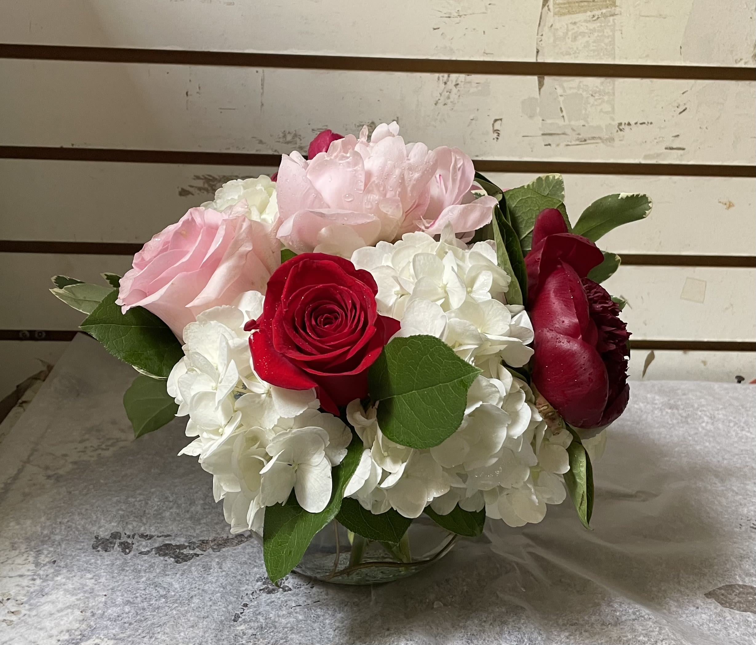 Pink and red roses with white hydrangeas in a glass vase