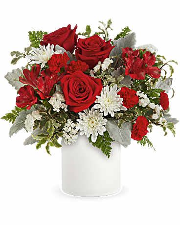 Red roses, red carnations, and white mums arranged in a white cylinder vase