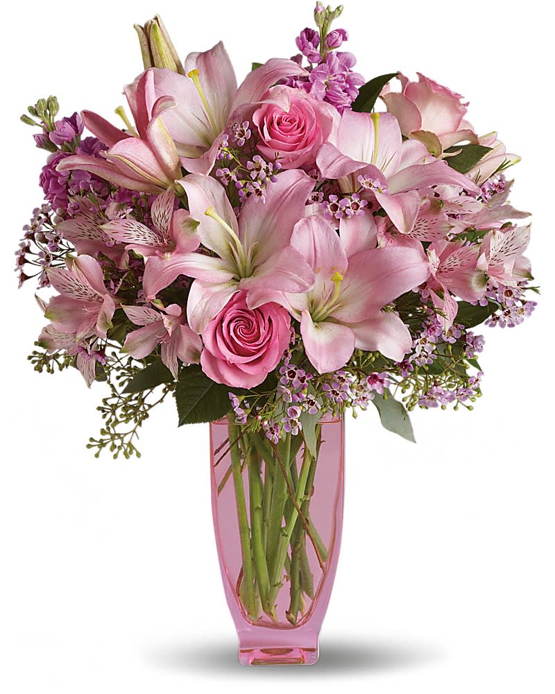 Pink lilies and roses arranged in a pink glass vase