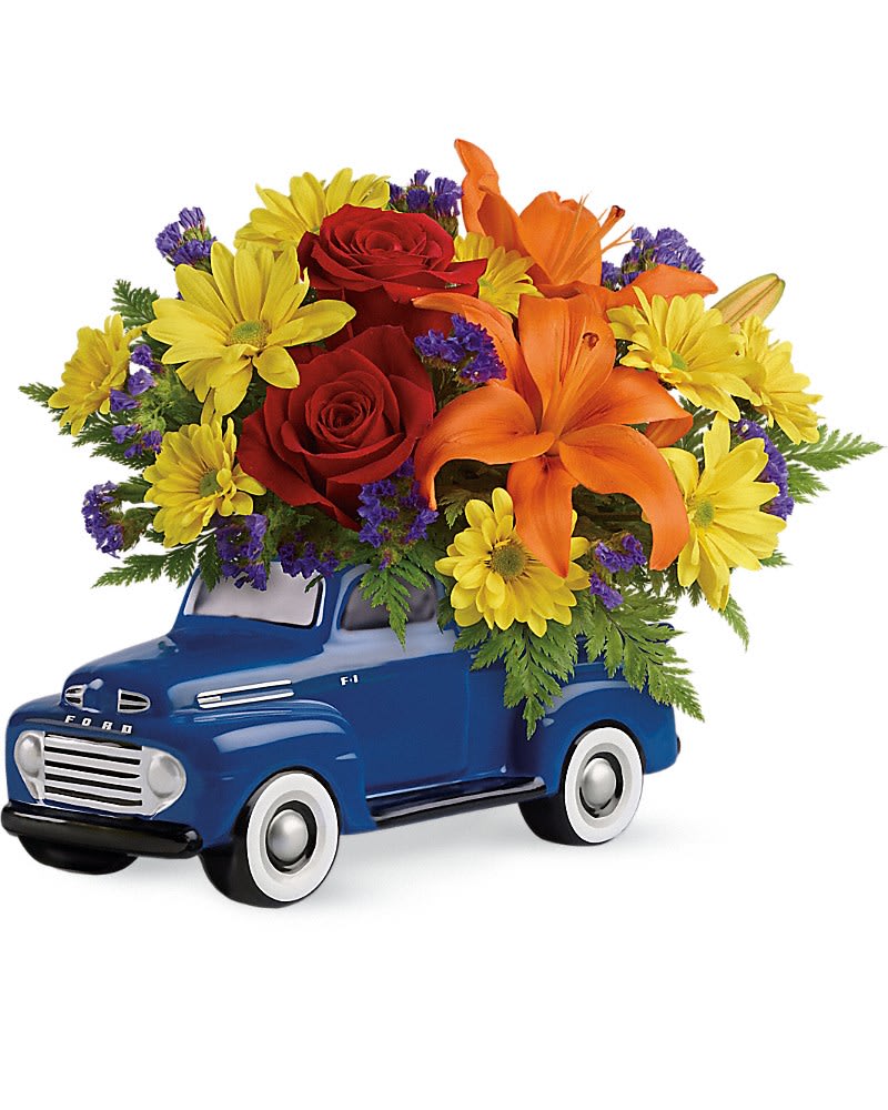 Bouquet of red roses, yellow daisies, and orange lilies in a blue truck container