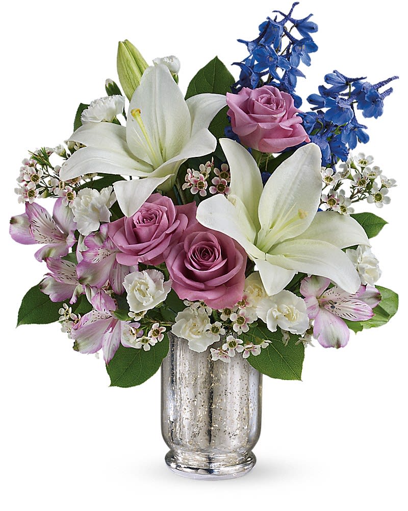 Bouquet of white lilies, pink roses, and blue flowers in a glass vase