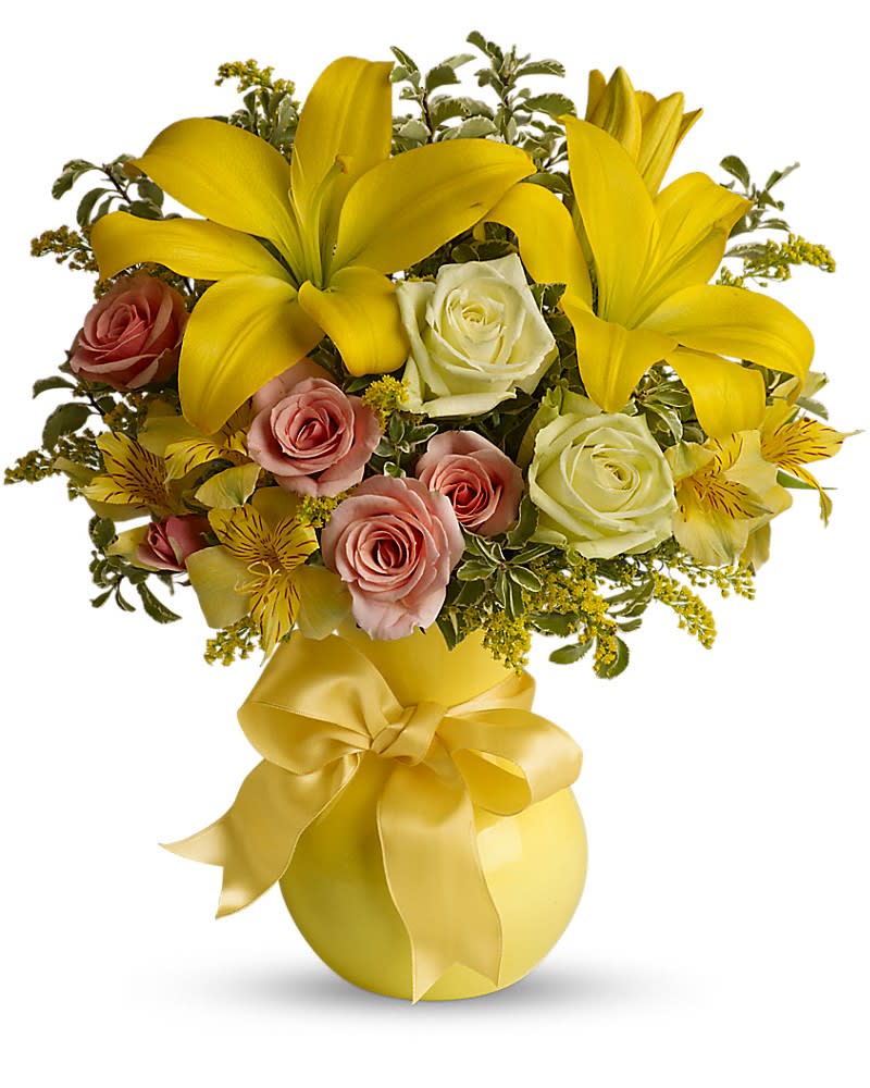 Yellow lilies and pink roses in a yellow vase with a ribbon