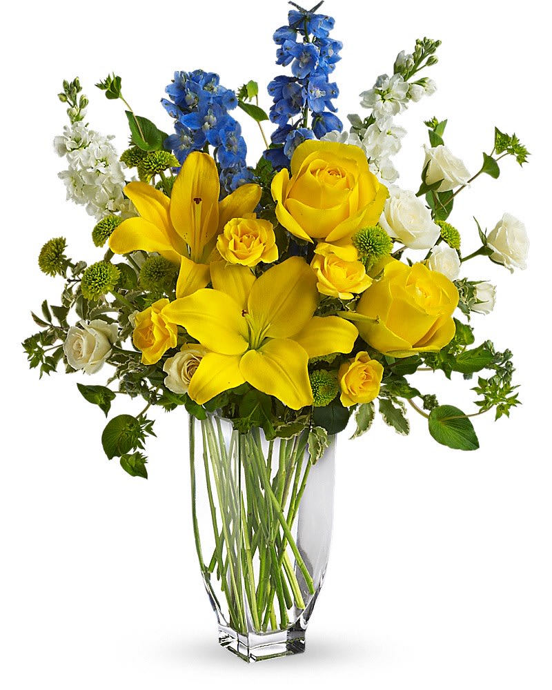 Yellow roses and lilies with blue and white flowers in a clear vase