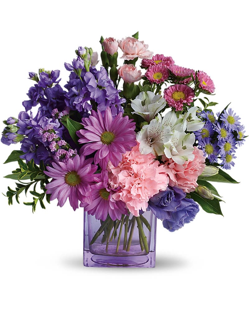 Mixed bouquet of purple daisies, pink carnations and white blooms in a lavender glass cube vase