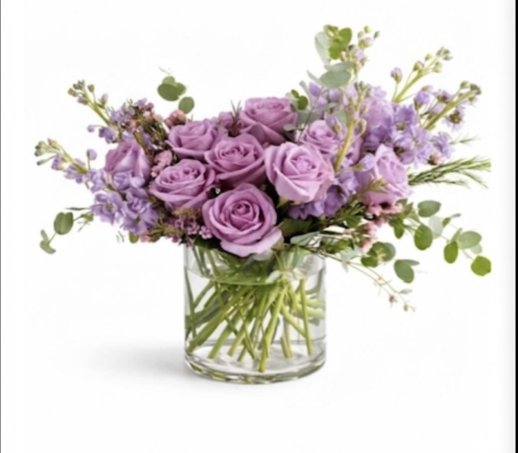 Lavender roses and purple flowers in a clear glass vase