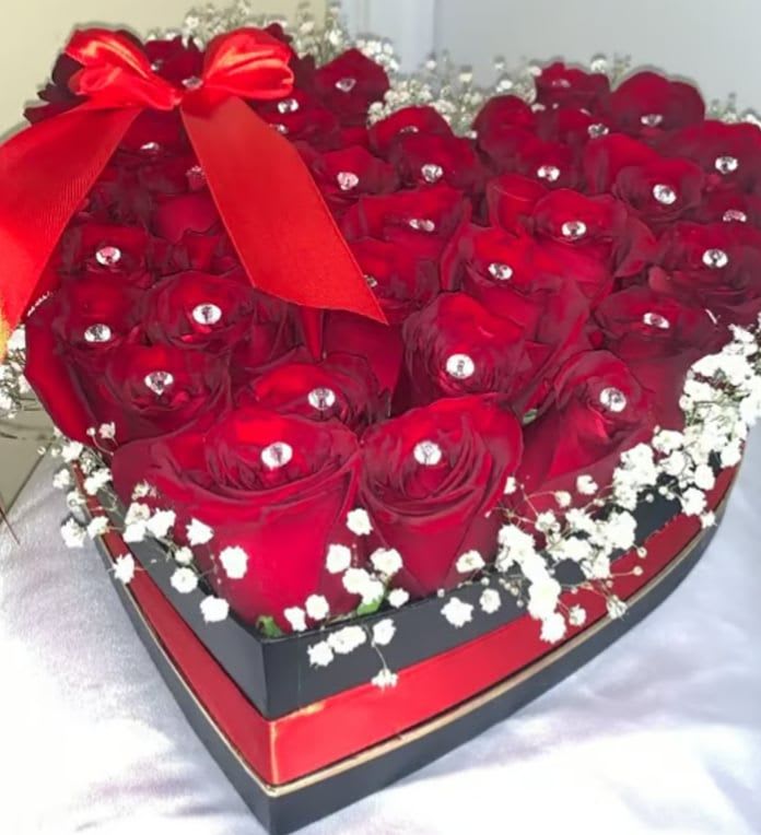 Heart-shaped box filled with red roses and a red ribbon bow