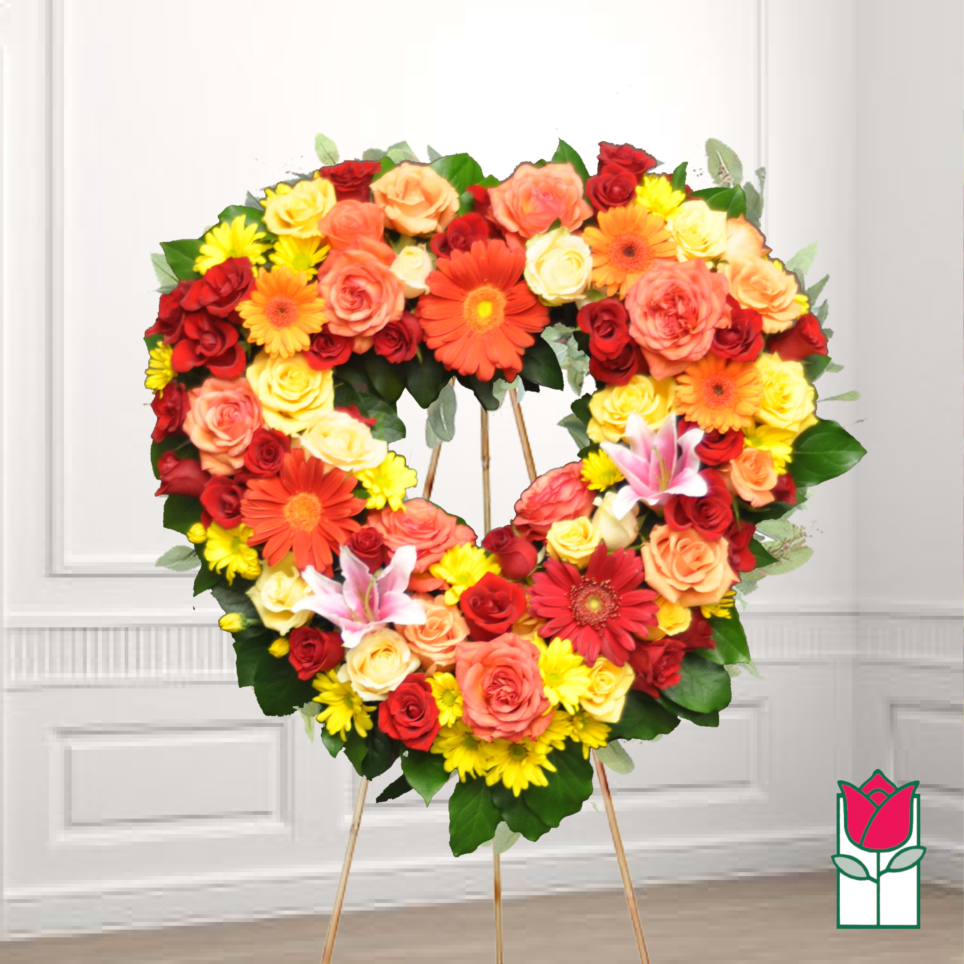 Heart-shaped floral wreath with roses, daisies, and lilies on an easel
