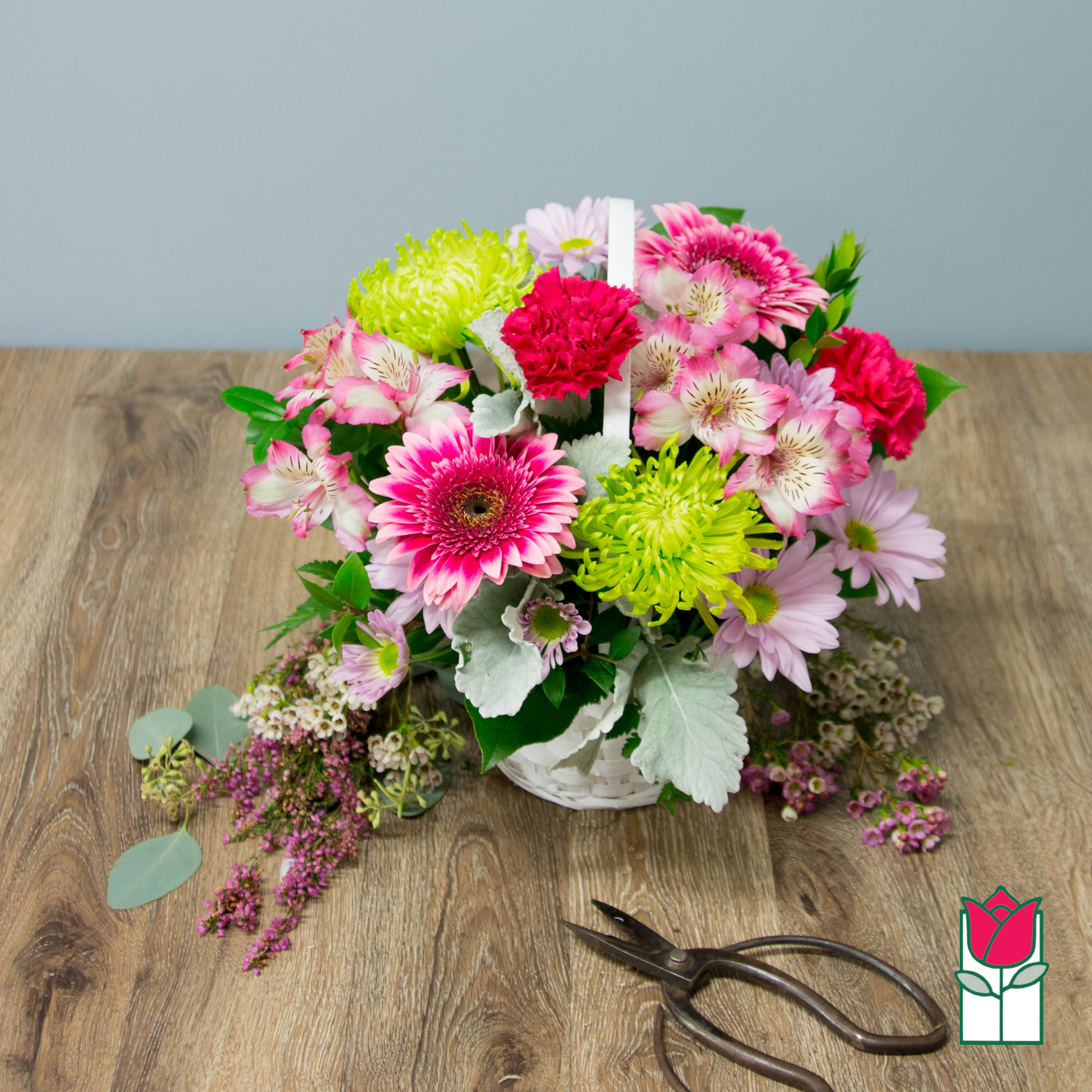 Basket arrangement of pink and lime flowers with a white handle