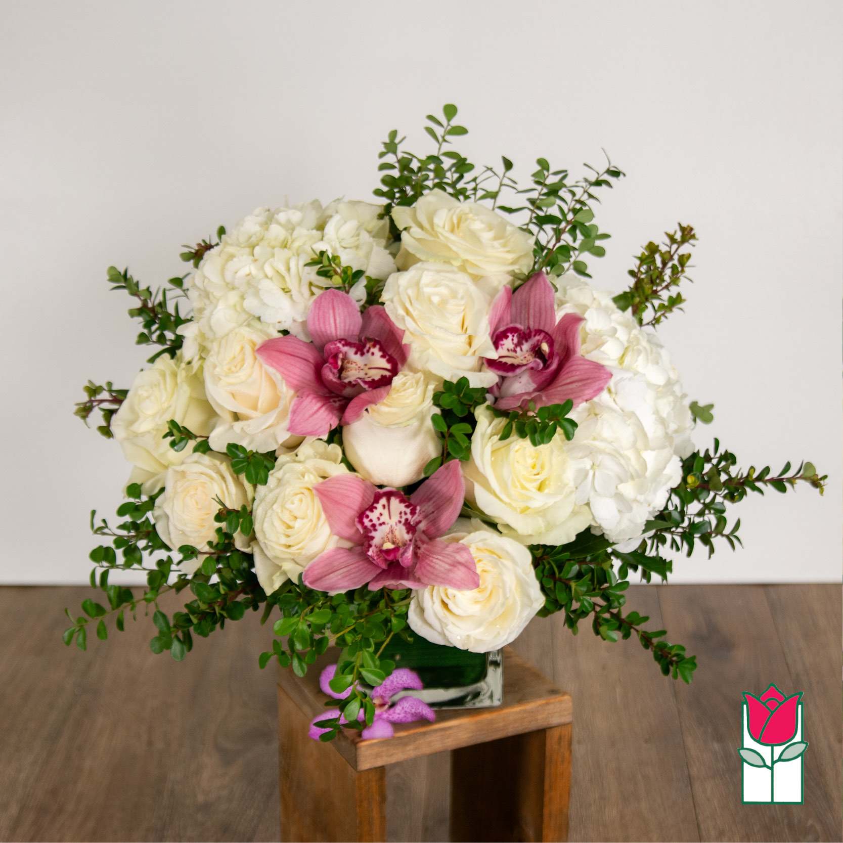 White roses and hydrangeas with pink orchids in a glass vase