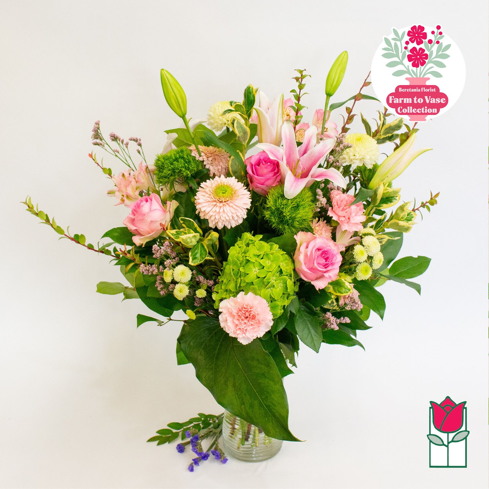 Pink lilies and roses in a glass vase with mixed blooms