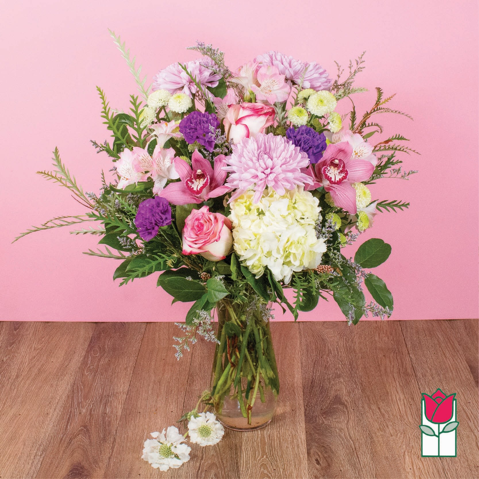 Mixed pink, white, and purple flowers in a clear glass vase