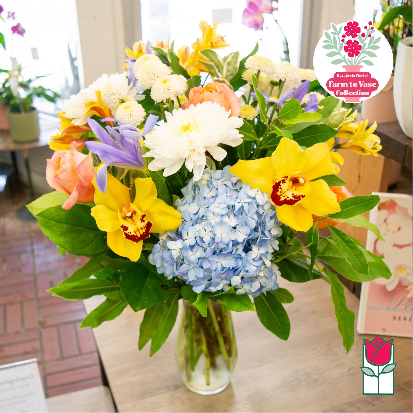 Mixed bouquet in a clear glass vase with blue hydrangea and yellow orchids