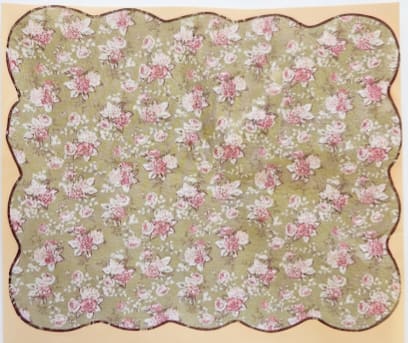Floral-patterned scalloped fabric in pink and white on a green background