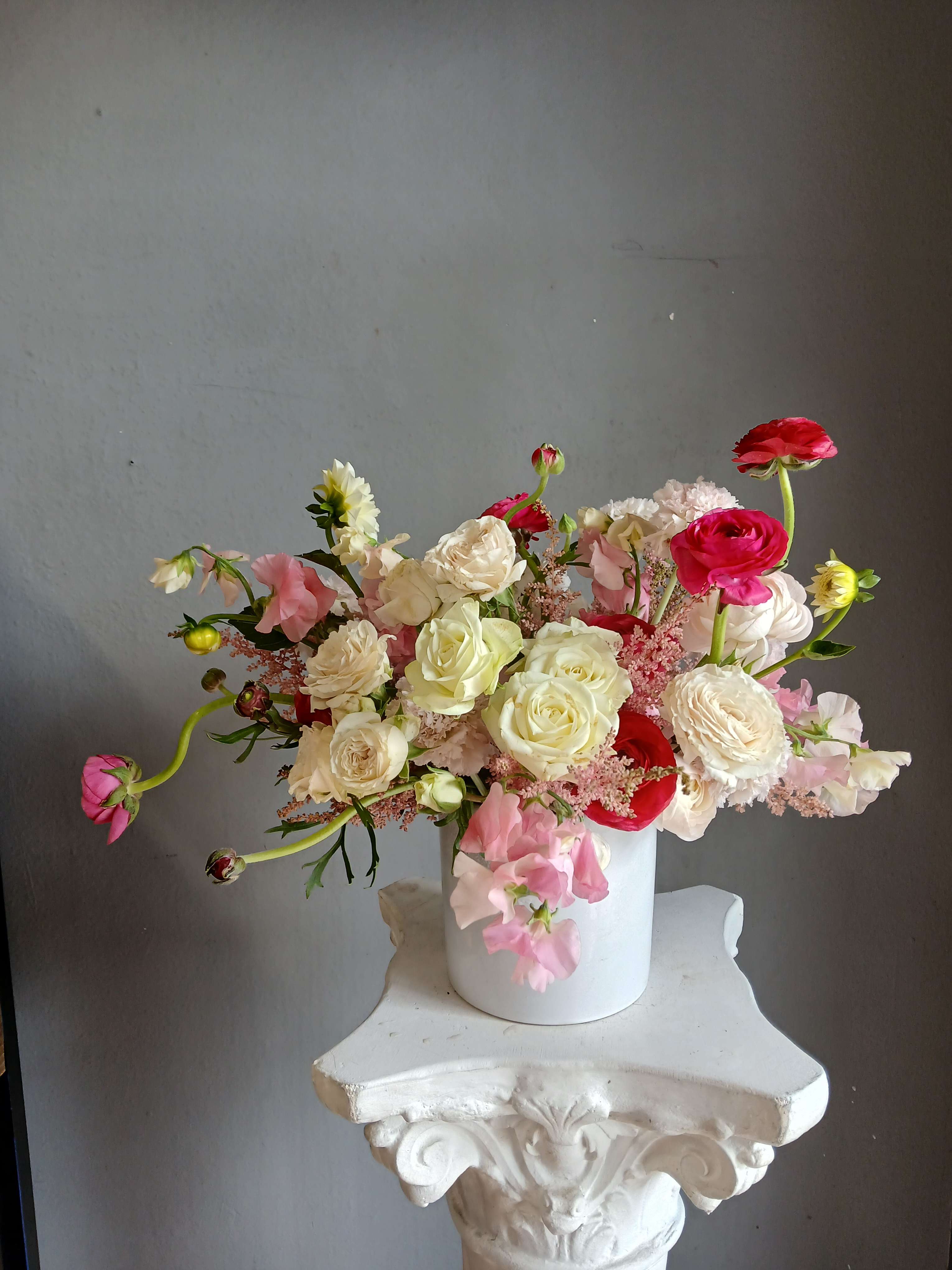Mixed pink and white flowers arranged in a white vase