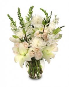 White floral arrangement in a glass vase with tall green spikes