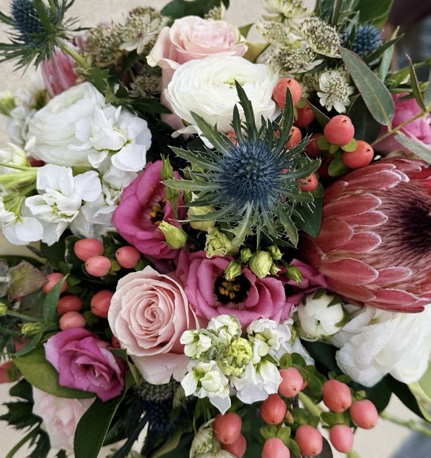 Mixed bouquet with pink and white flowers and a blue thistle bloom