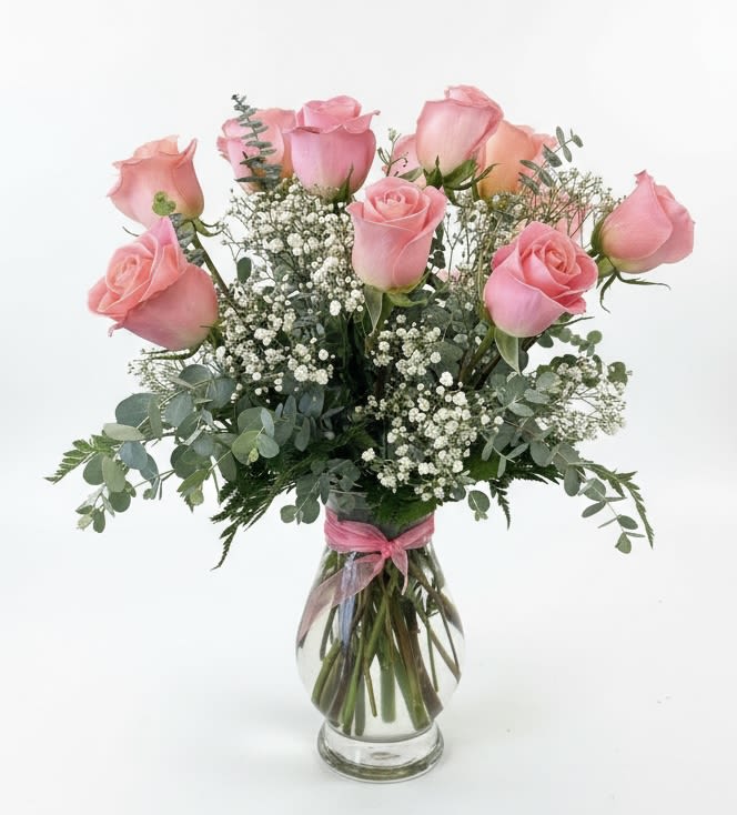 Pink roses arranged in a clear glass vase with baby's breath