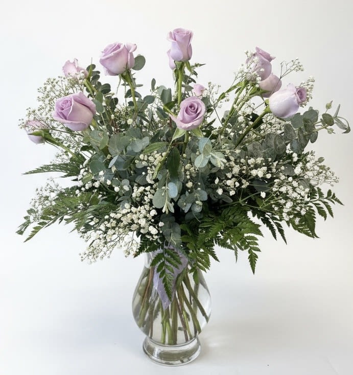 Lavender roses in a clear glass vase with baby's breath