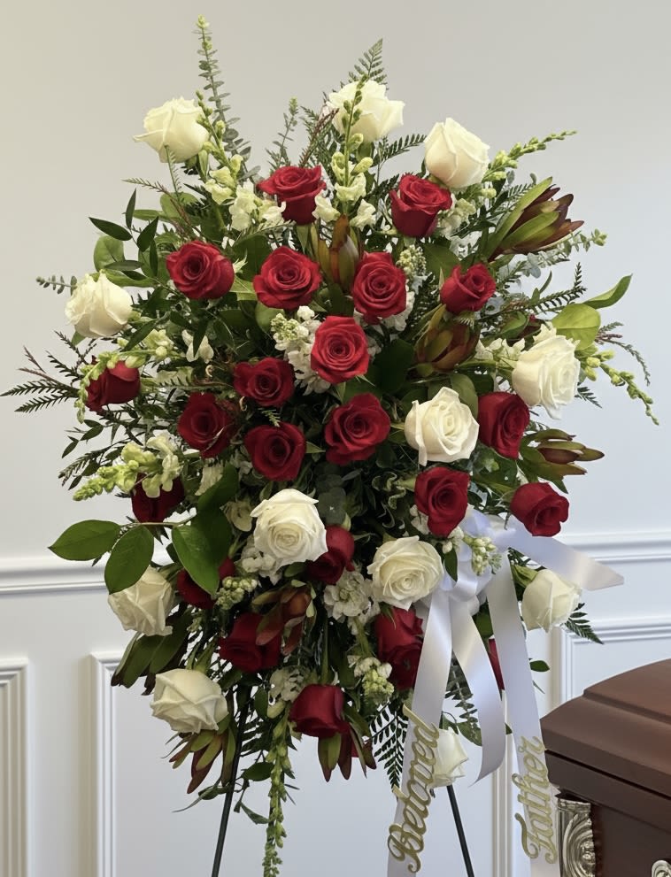 Standing spray of red and white roses with ribbon on an easel