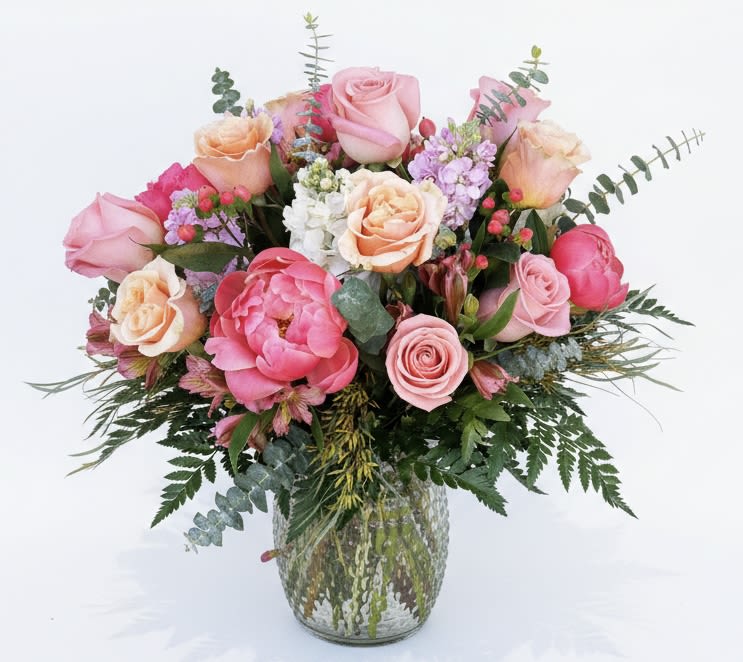 Pink and peach roses arranged in a glass vase