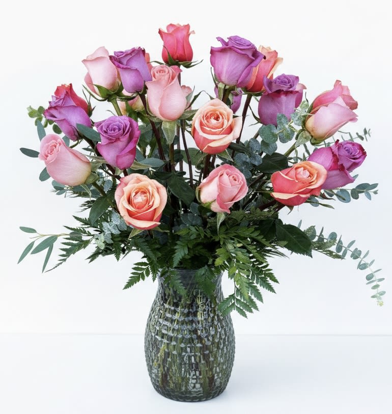 Pink and purple roses arranged in a glass vase