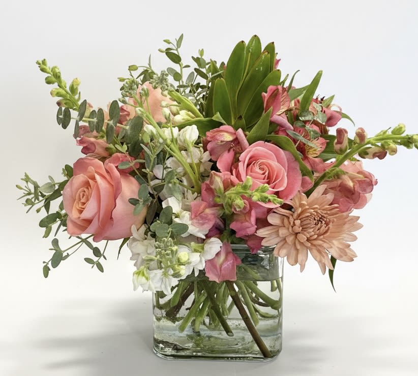 Pink roses and mixed flowers arranged in a clear glass vase