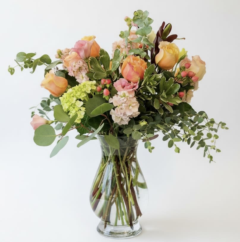 Mixed bouquet of peach and pink roses in a clear glass vase