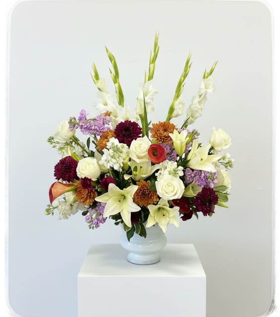 Mixed floral arrangement in a white vase with tall white spikes