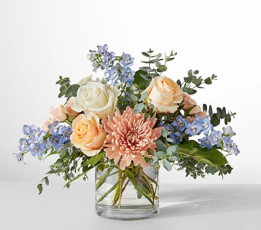 Bouquet of peach and white roses with a pink chrysanthemum in a glass vase